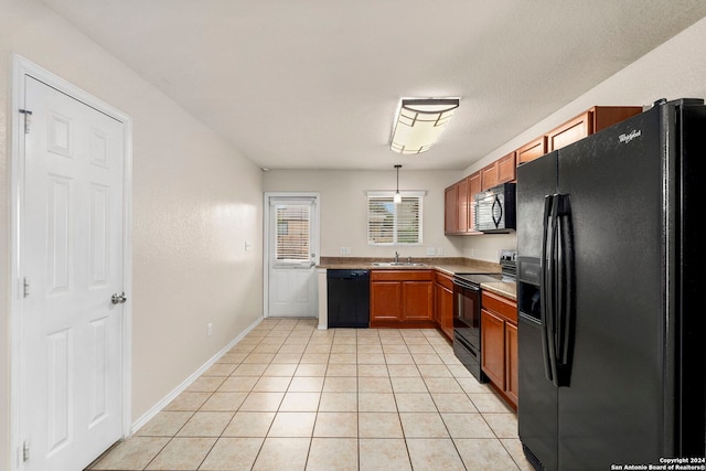 kitchen featuring pendant lighting, light tile patterned floors, sink, and black appliances