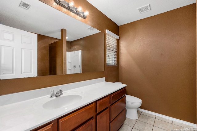 bathroom with tile patterned floors, vanity, a textured ceiling, toilet, and a shower