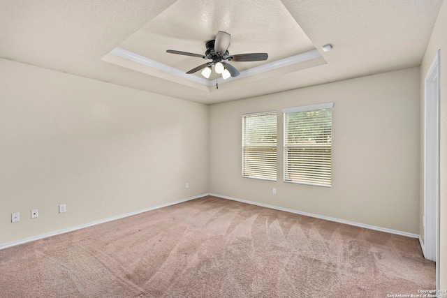 carpeted empty room featuring a textured ceiling, ceiling fan, crown molding, and a tray ceiling