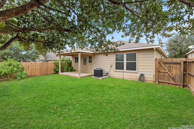 rear view of property with a patio, central AC unit, and a yard