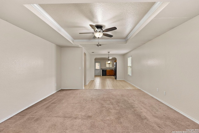 unfurnished living room featuring ceiling fan, light colored carpet, a raised ceiling, and crown molding