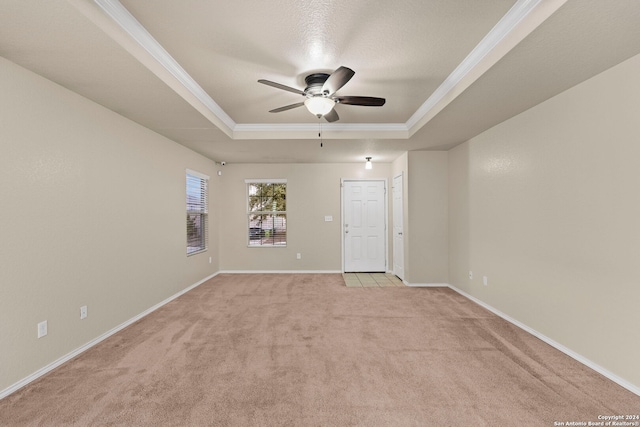 carpeted empty room with ceiling fan, a raised ceiling, and ornamental molding