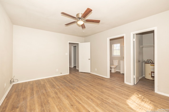 unfurnished bedroom featuring ensuite bathroom, ceiling fan, light wood-type flooring, and a walk in closet