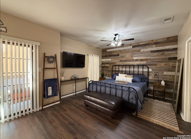 bedroom with wooden walls, dark wood-type flooring, an accent wall, and a ceiling fan