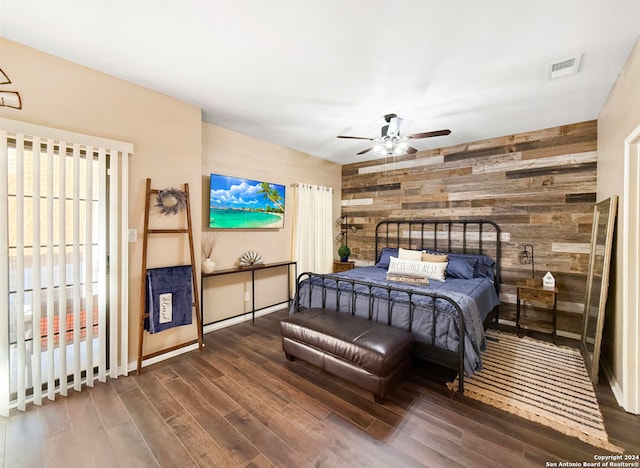 bedroom with dark wood-type flooring, wood walls, and ceiling fan