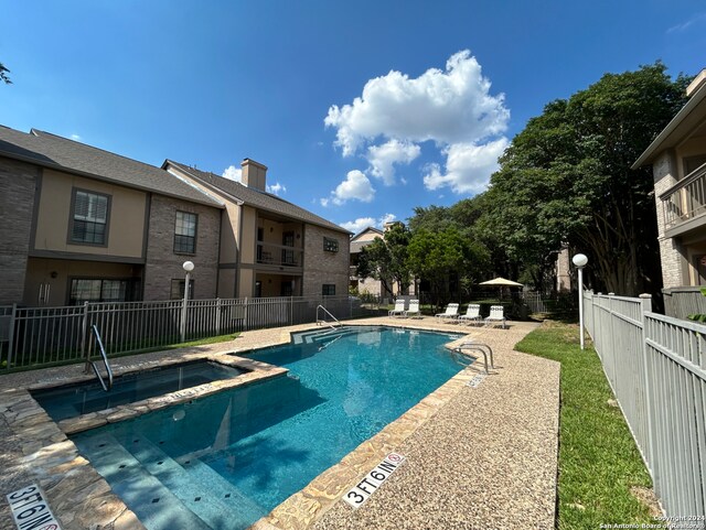 view of pool with fence, a pool with connected hot tub, and a patio