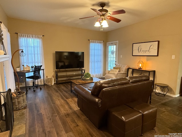 living area featuring ceiling fan, healthy amount of natural light, and dark wood-style flooring