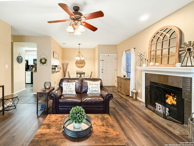 living room featuring ceiling fan, a tiled fireplace, and dark hardwood / wood-style flooring