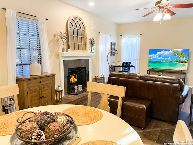 dining room with a fireplace, plenty of natural light, ceiling fan, and dark tile patterned floors