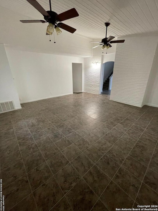 unfurnished room featuring ceiling fan, wood ceiling, and brick wall