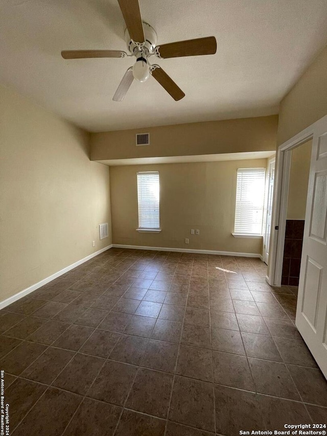 tiled empty room with a textured ceiling, plenty of natural light, and ceiling fan