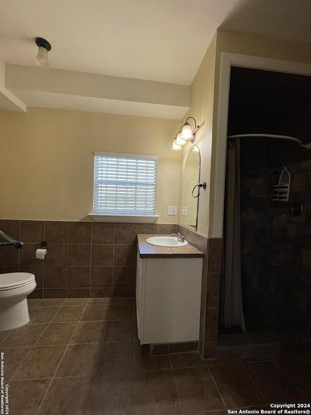 bathroom with tile walls, tile patterned flooring, walk in shower, and vanity