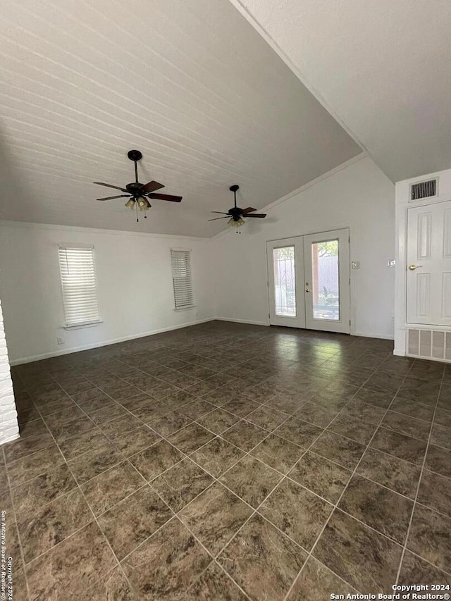 unfurnished living room with french doors, ceiling fan, dark tile patterned floors, and lofted ceiling