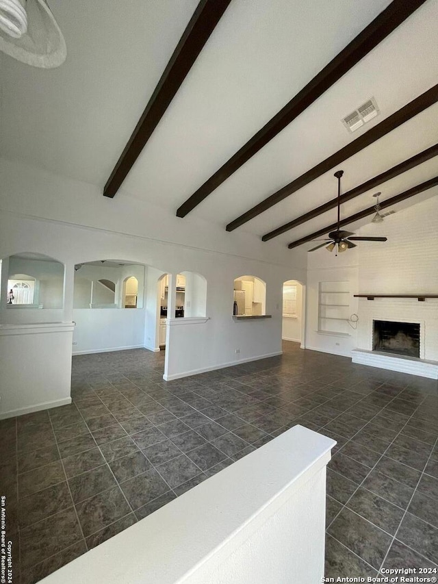 living room with ceiling fan, beam ceiling, and dark tile patterned flooring