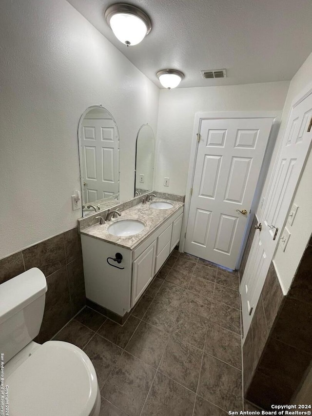 bathroom featuring tile walls, tile patterned floors, vanity, a textured ceiling, and toilet