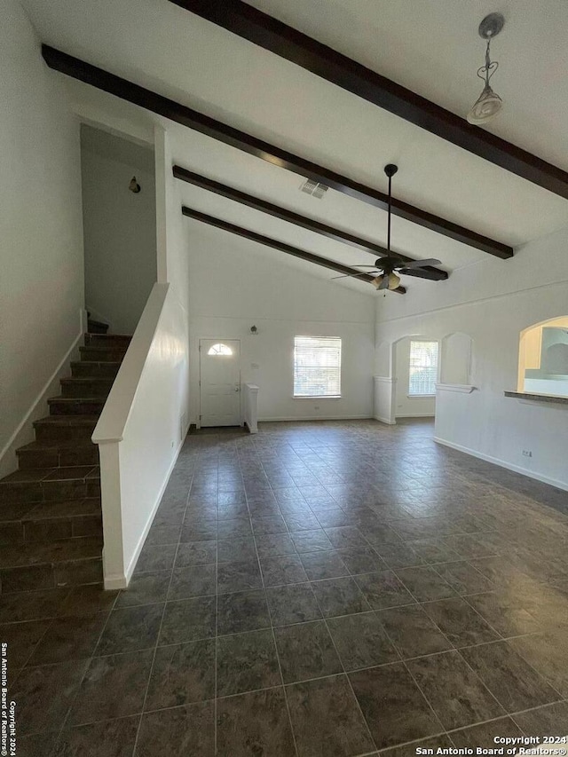 unfurnished living room with lofted ceiling with beams, dark tile patterned floors, and ceiling fan