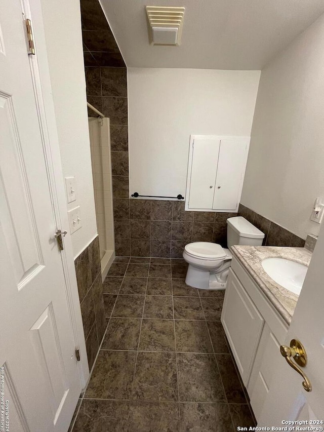 bathroom featuring tile walls, tile patterned floors, a shower with curtain, vanity, and toilet