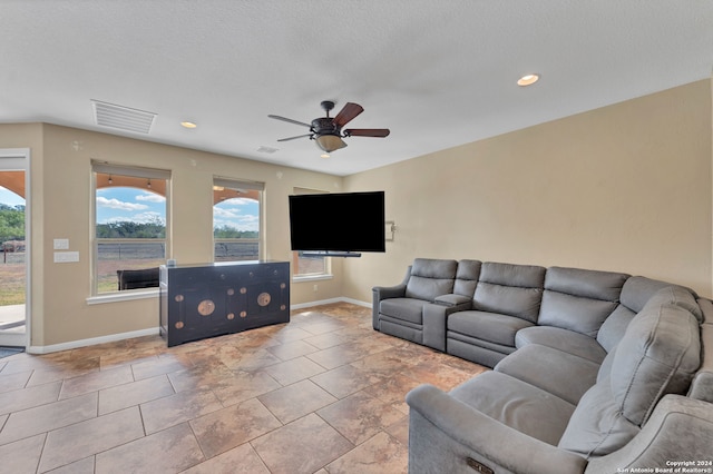 living room with light tile patterned flooring, ceiling fan, and a textured ceiling