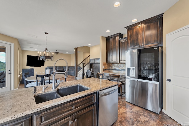 kitchen featuring sink, appliances with stainless steel finishes, dark brown cabinets, a notable chandelier, and pendant lighting