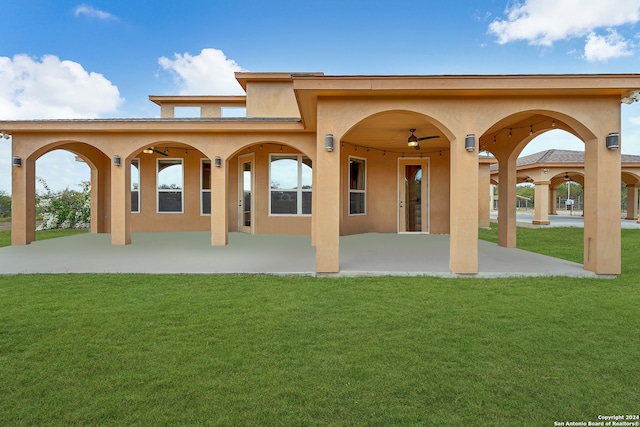 rear view of house with ceiling fan, a yard, and a patio area