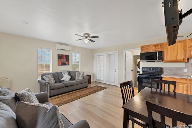 living room featuring ceiling fan, a wall mounted AC, and light hardwood / wood-style floors