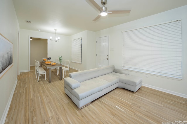 living room featuring ceiling fan with notable chandelier and light hardwood / wood-style flooring