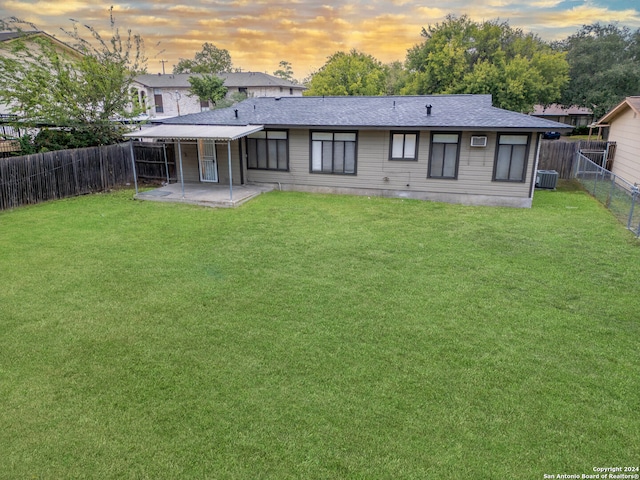 back house at dusk featuring a yard, a patio, and cooling unit