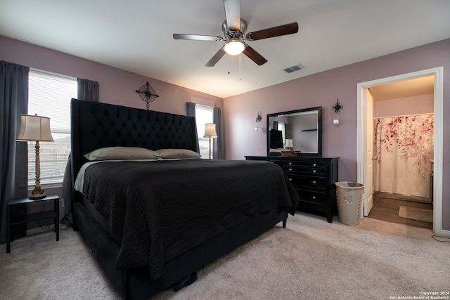 bedroom with light carpet, ceiling fan, and connected bathroom