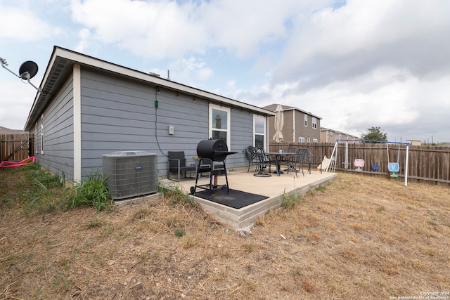 rear view of house with central air condition unit, a lawn, and a patio