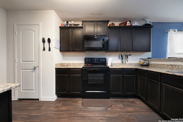 kitchen featuring dark hardwood / wood-style floors, a textured ceiling, black appliances, and light stone counters