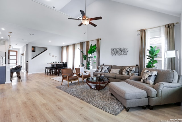 living room with ceiling fan, light wood-type flooring, and high vaulted ceiling