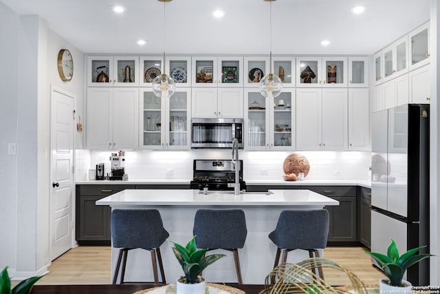 kitchen with gray cabinetry, pendant lighting, an island with sink, and appliances with stainless steel finishes