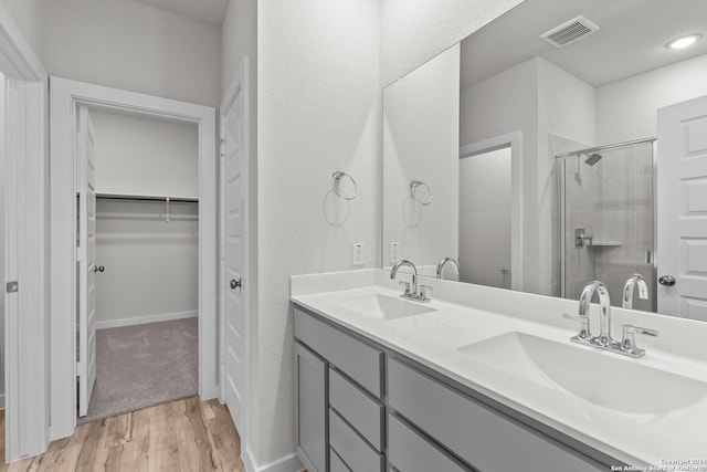 bathroom with hardwood / wood-style floors, vanity, and a shower with door