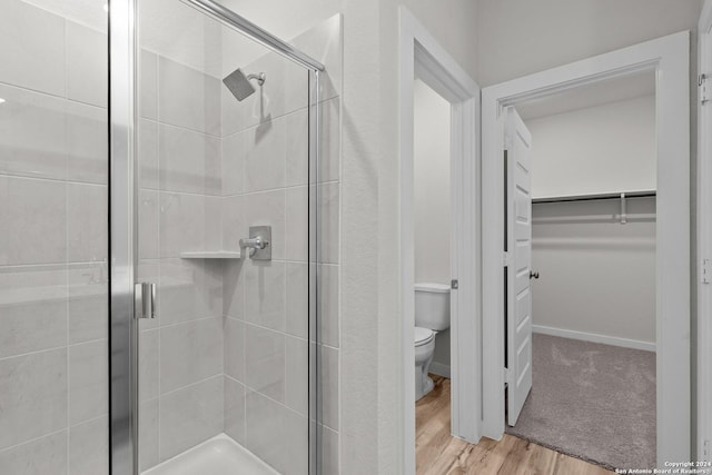 bathroom featuring toilet, hardwood / wood-style floors, and walk in shower