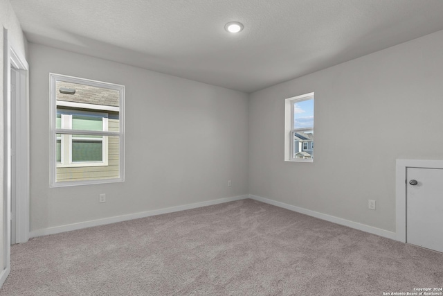 spare room featuring a textured ceiling and light colored carpet