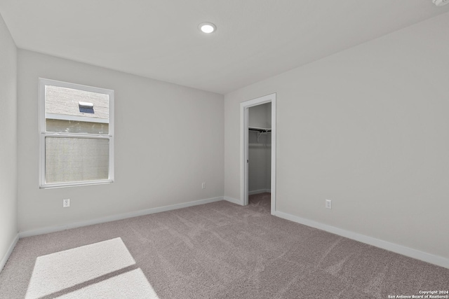 unfurnished bedroom featuring a spacious closet, a closet, and carpet