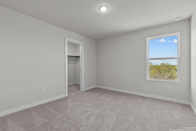 unfurnished bedroom featuring a spacious closet, light carpet, and a closet