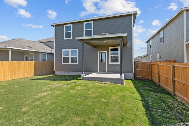 rear view of property featuring a lawn and a patio area