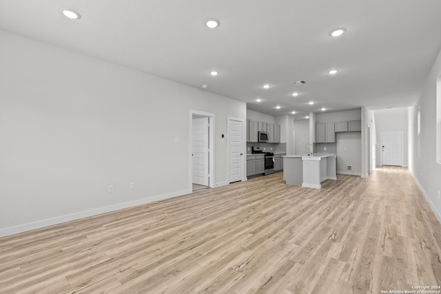 unfurnished living room with light wood-type flooring and sink