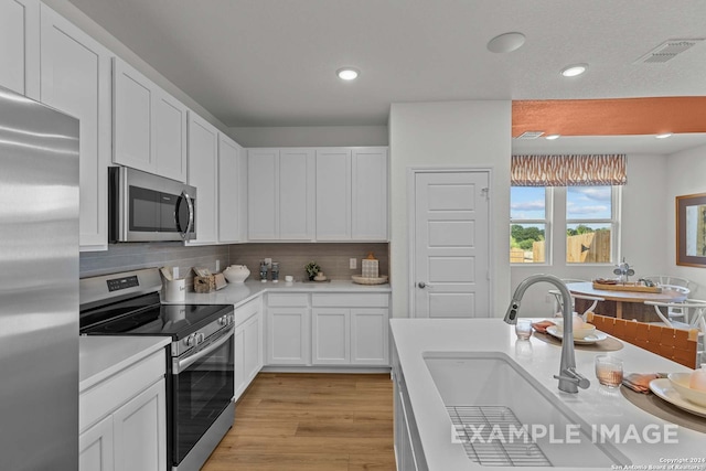 kitchen featuring white cabinetry, sink, appliances with stainless steel finishes, and light hardwood / wood-style flooring