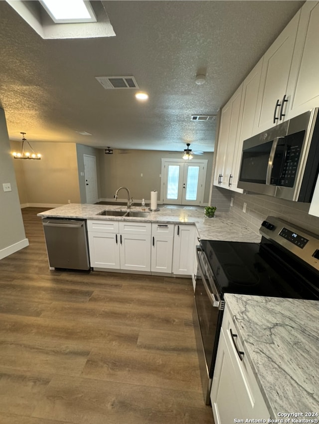 kitchen featuring sink, dark hardwood / wood-style flooring, kitchen peninsula, white cabinets, and appliances with stainless steel finishes