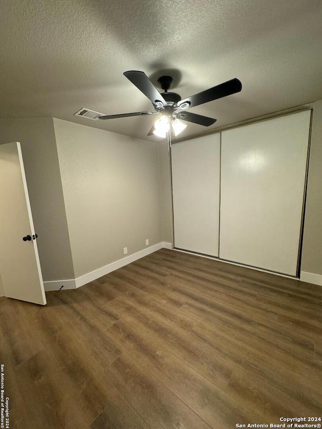 unfurnished bedroom featuring a closet, a textured ceiling, hardwood / wood-style flooring, and ceiling fan