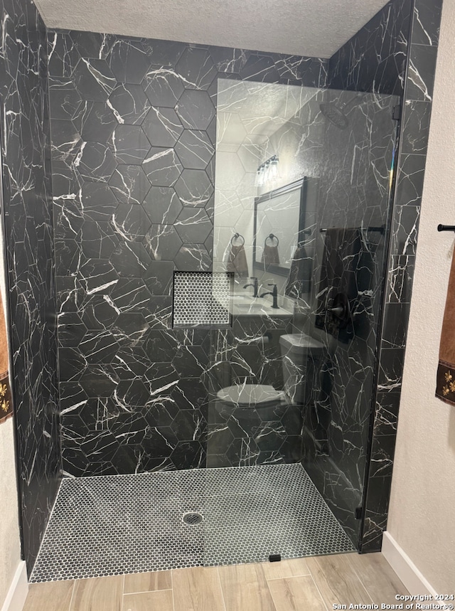 bathroom featuring a textured ceiling and tiled shower