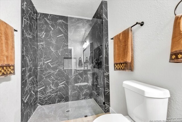 bathroom with a tile shower, a textured ceiling, and toilet