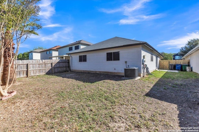 rear view of property with central AC and a lawn