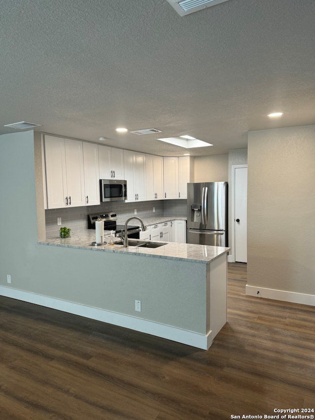 kitchen featuring white cabinets, appliances with stainless steel finishes, kitchen peninsula, and sink