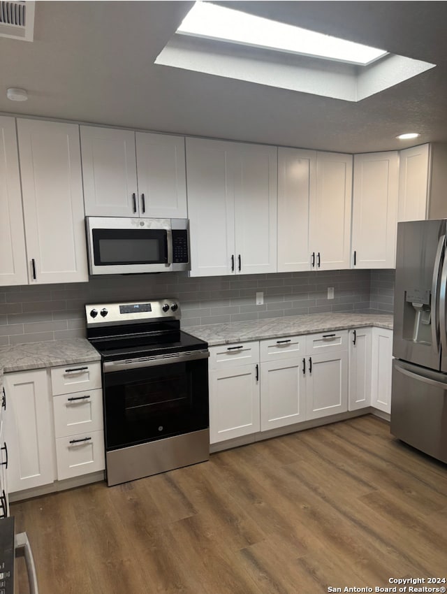 kitchen featuring decorative backsplash, dark hardwood / wood-style flooring, white cabinetry, and appliances with stainless steel finishes