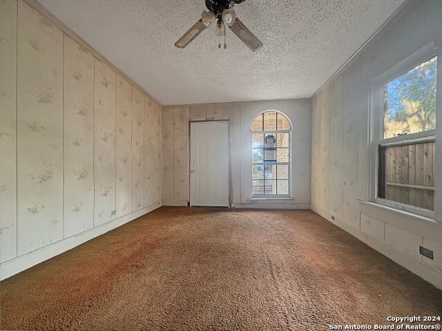 carpeted empty room featuring ceiling fan and a textured ceiling