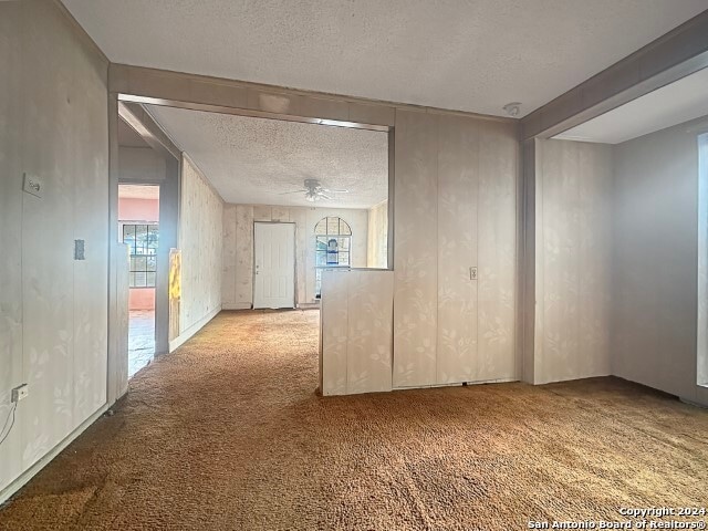 carpeted spare room with a textured ceiling and ceiling fan