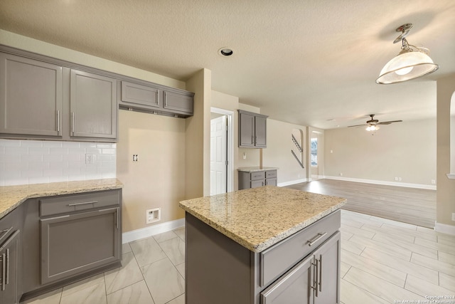 kitchen with gray cabinetry, pendant lighting, and light stone counters